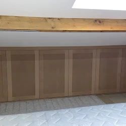 Bespoke fitted alcove storage units built under a sloped ceiling